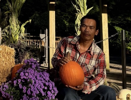Chaofeng Ge, 32, seated outdoors holding a pumpkin. Photo provided, via WPSU.